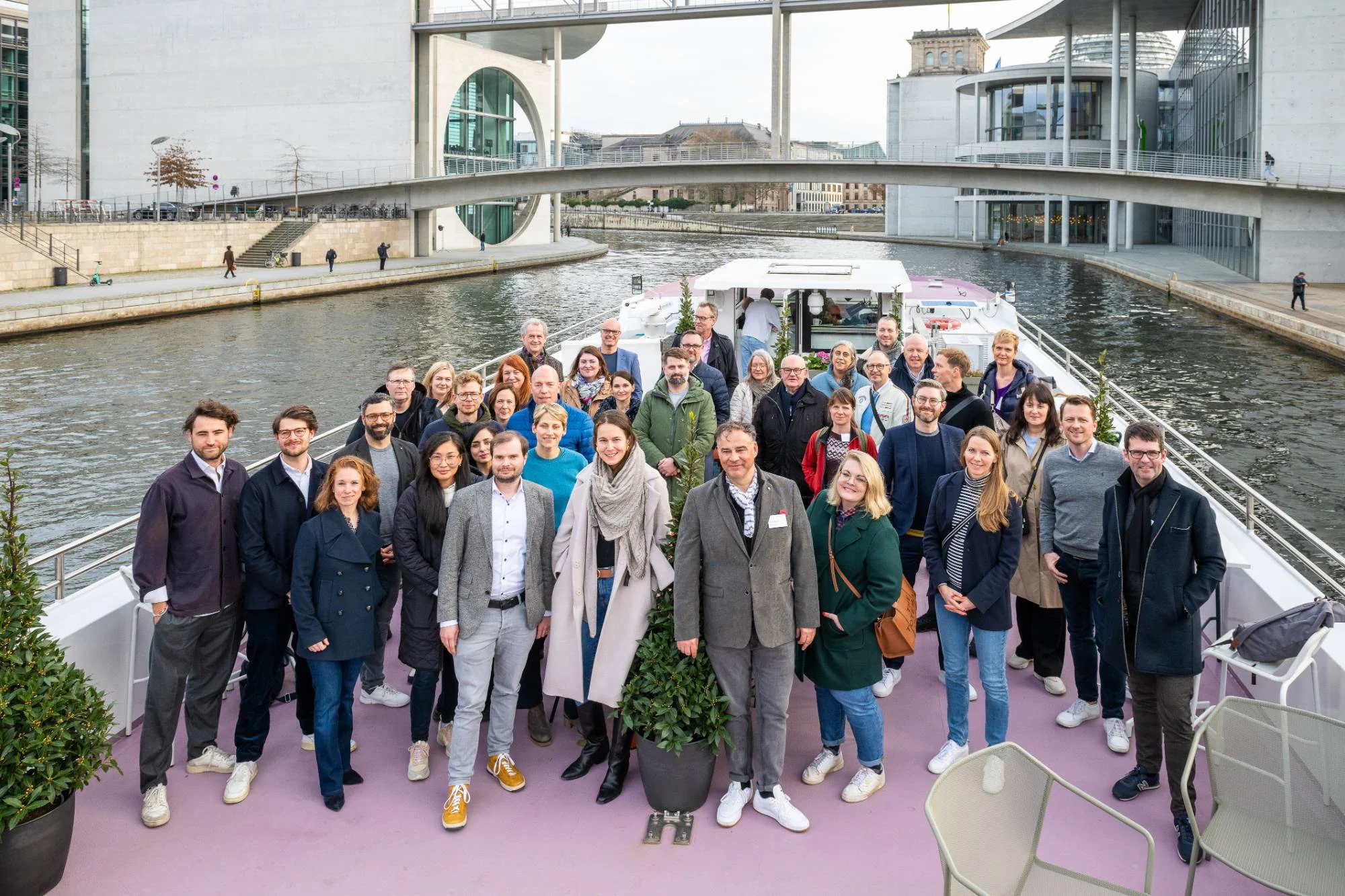 Teilnehmende der Newsletter Tour auf einem Boot auf der Spree vor dem Berliner Regierungsviertel